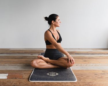 Woman sitting on wooden floor doing yoga