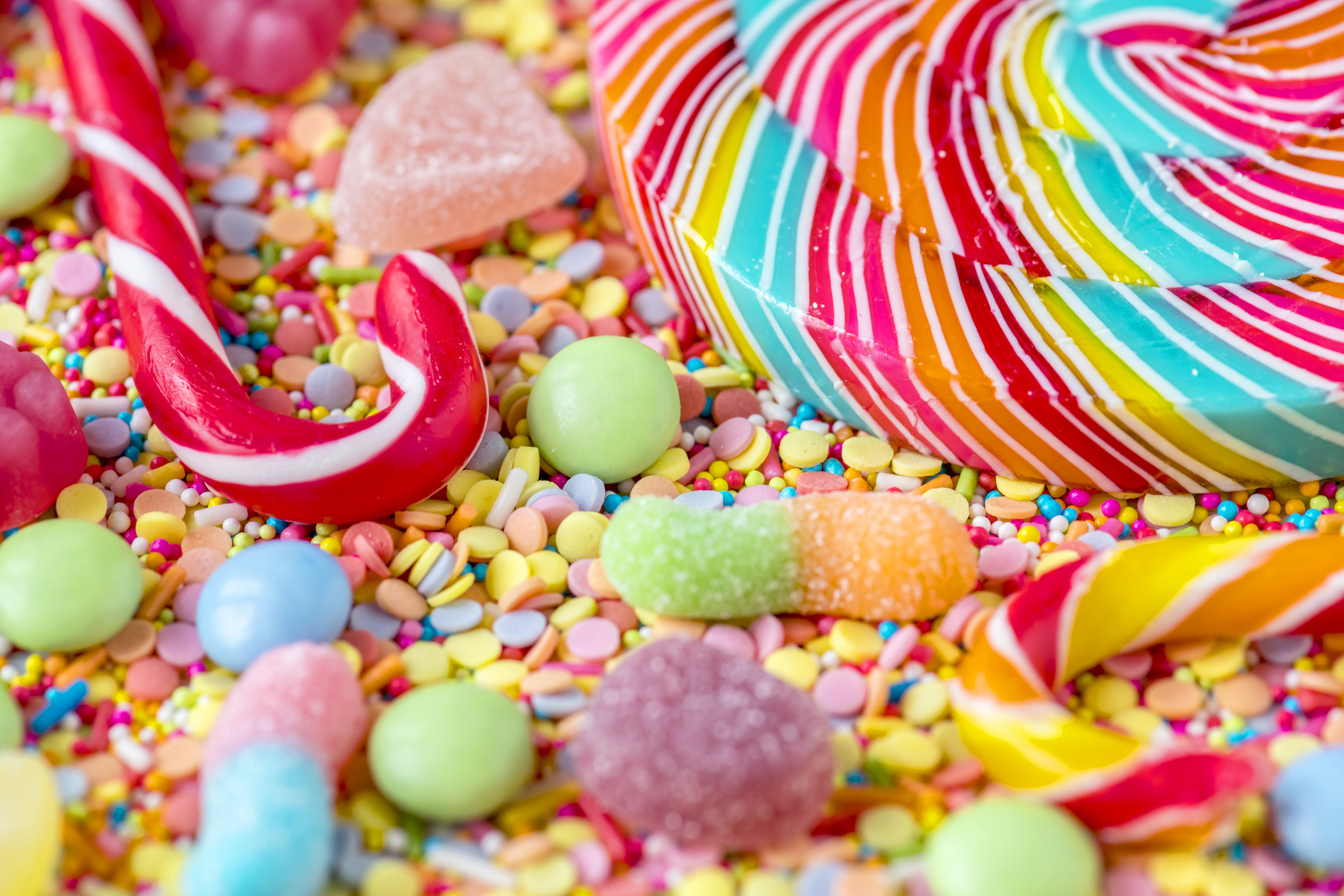 Close up of candycane and lollipop on a colorful sweets backgrou
